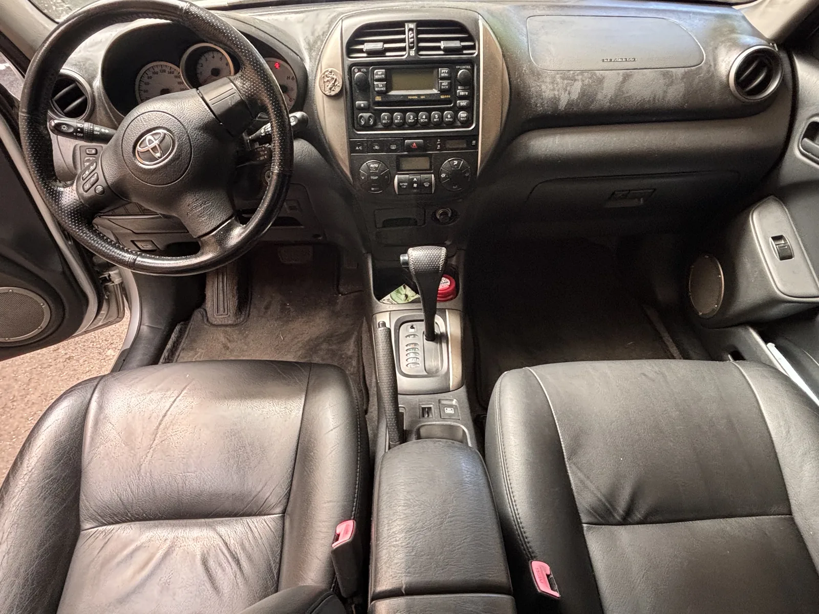 Habitacle Toyota RAV4 avant nettoyage — tableau de bord poussiéreux, tapis sales